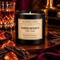 Maison Stee Ember Reserve candle in a glass matte‑black vessel, lit on a dark wooden surface with soft, warm light. Minimal, elegant styling conveys a luxurious, intimate mood.
